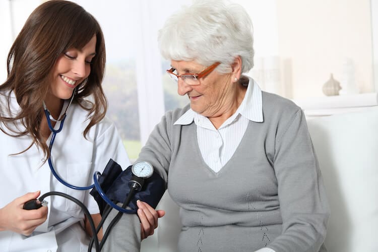 A nurse checking a senior woman’s blood pressure.