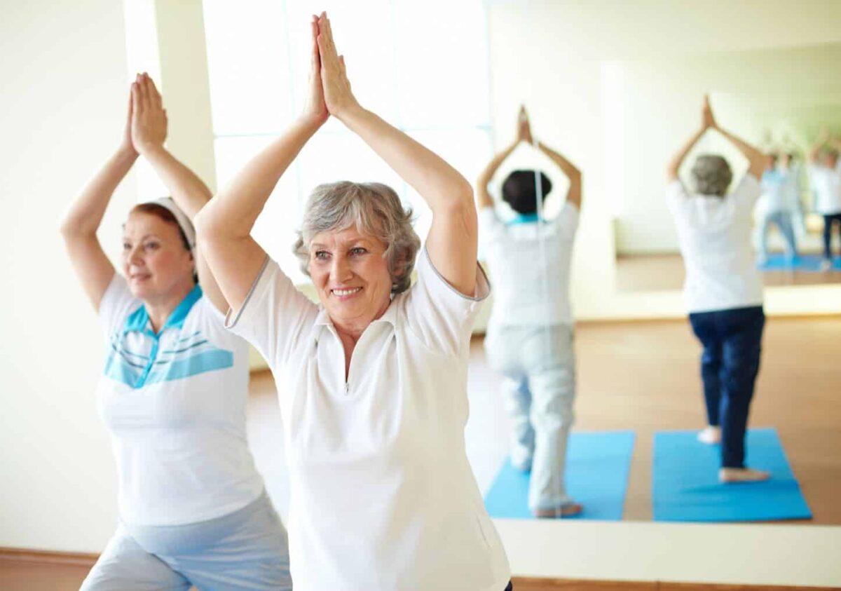 Two senior women enjoy working on balance during a yoga class.