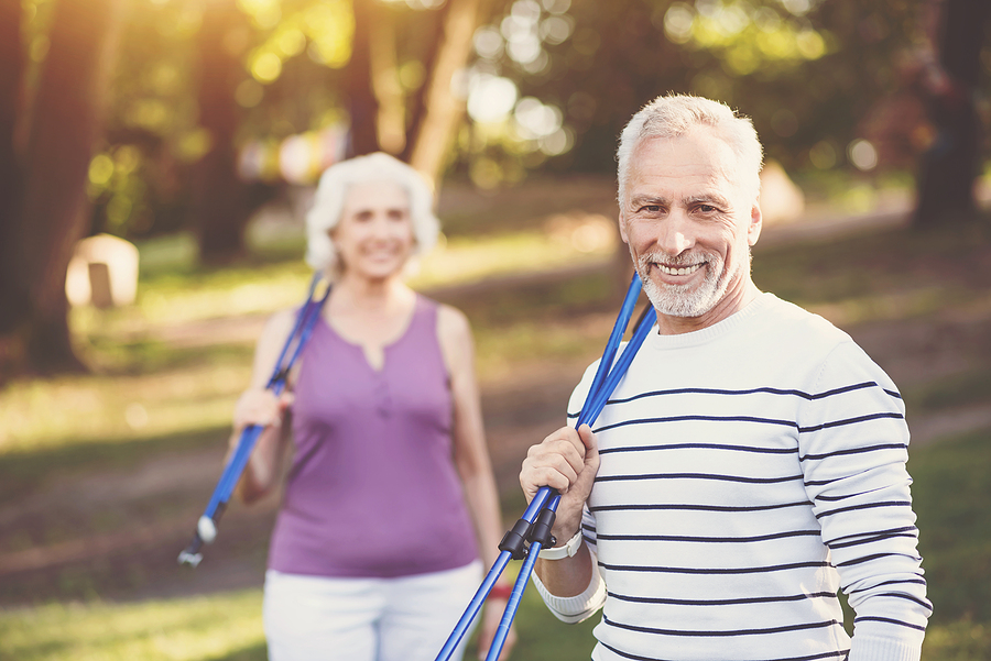 A senior couple carries their walking poles.