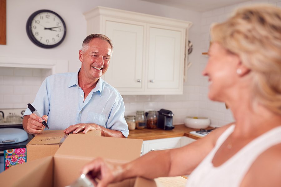 A senior couple packs up boxes.