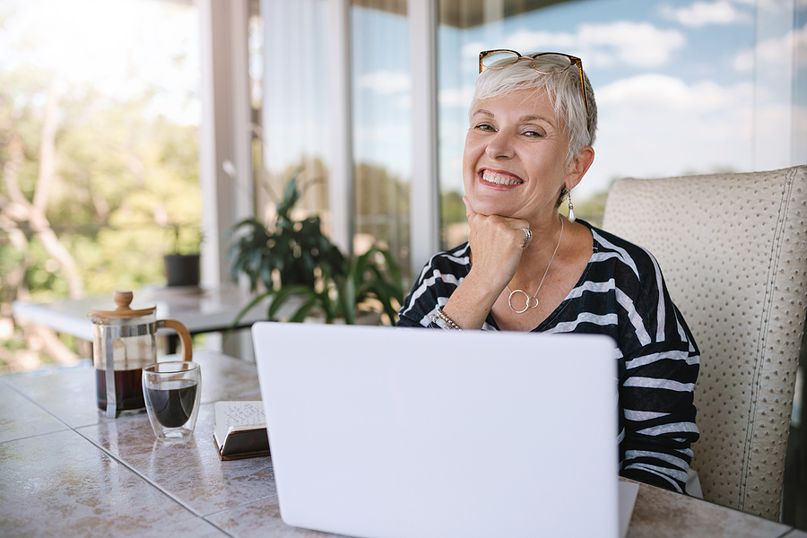 A senior woman smiles while working at her computer.