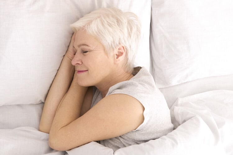 A senior woman is tucked in bed for a good night’s sleep.