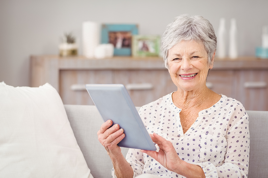 A senior woman uses a tablet.