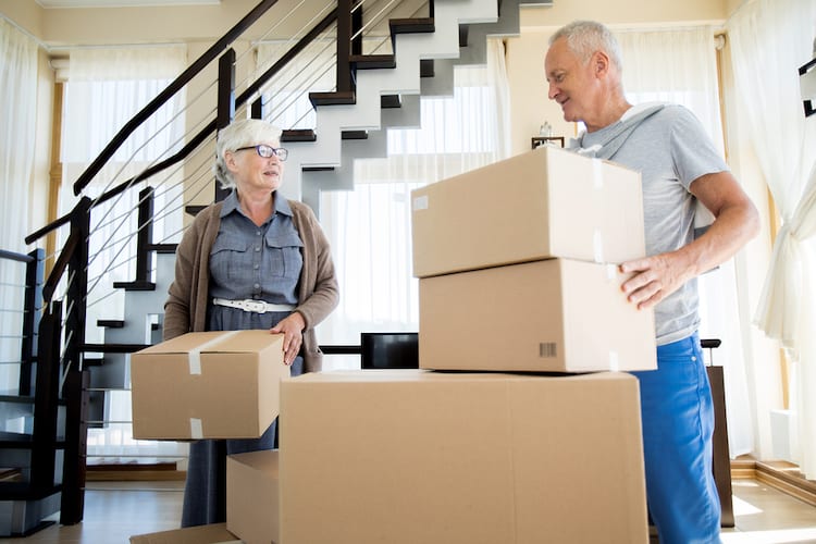 happy senior couple packing cardboard boxes while moving to new house