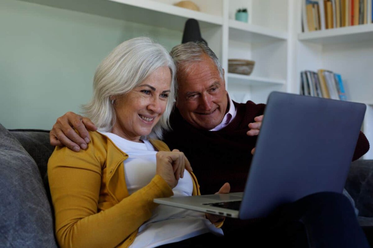 A senior couple enjoy a video chat with loved ones to practice social wellness.