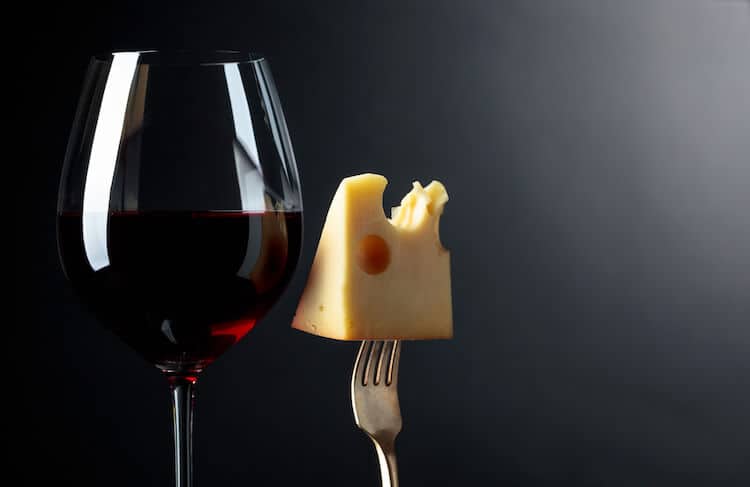 A piece of cheese and glass of wine at a pairing party.