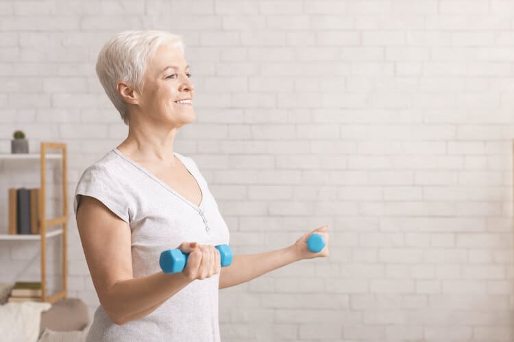A senior woman lifts hand weights at homes.