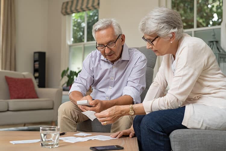 Senior couple looking at calculator and bills.