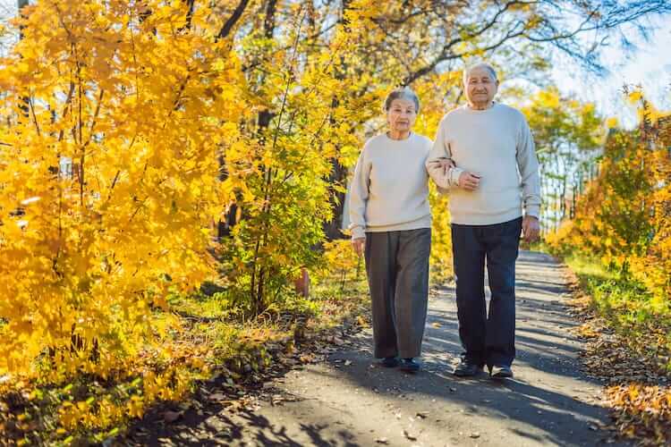 Happy senior couple talking a walk in the fall.