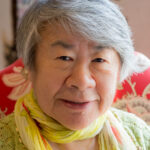 senior resident with a yellow scarf smiling at the camera