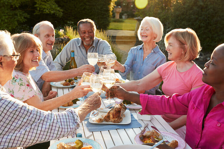 Seniors cheersing at a picnic table with white wine