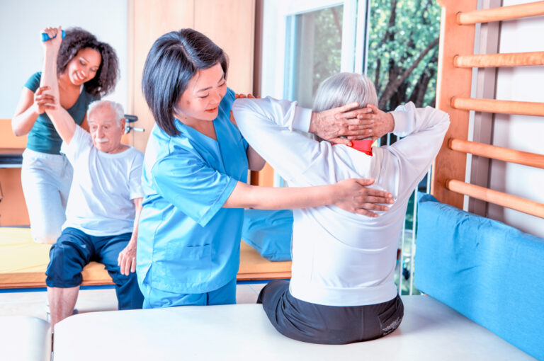 Two seniors and physical therapists receiving physical therapy treatment