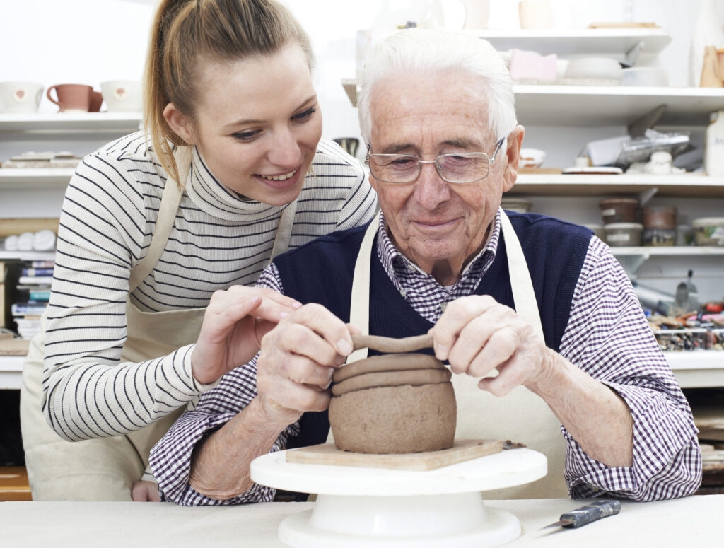 Senior Man With Teacher In Pottery Class
