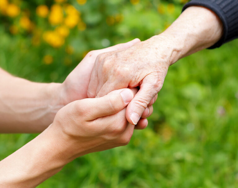 Doctor's hand holding a wrinkled elderly hand
