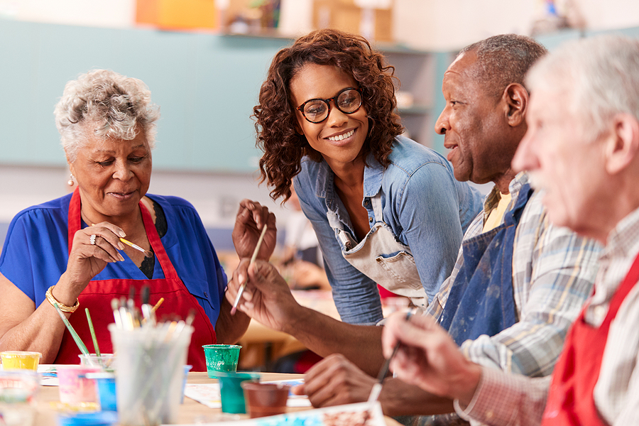 Group Of Retired Seniors Attending Art Class In Community Centre With Teacher
