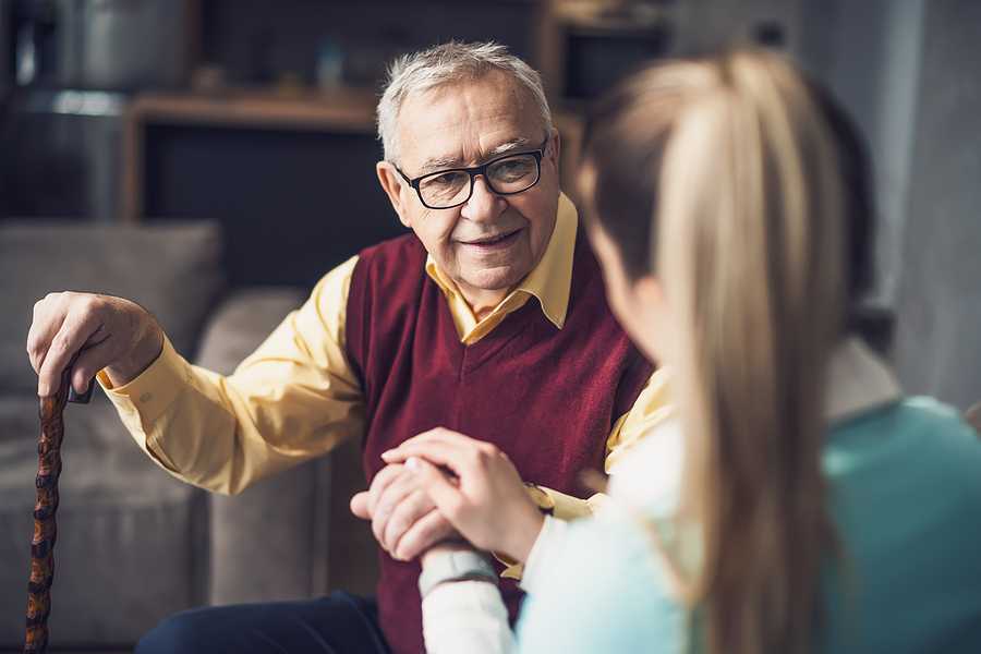 A senior man with a walker visits with his granddaughter