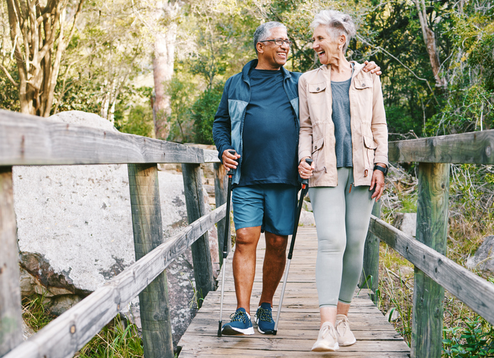 Older adult couple walking across a bridge during a spring trip